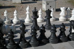 Close-up of the black and white chess pieces with shadows on the chess board, in light