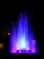 Beautiful fountain with colorful lights, among the darkness, at the night