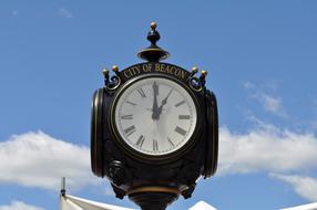 Beautiful, shiny, vintage clock on the street, under the blue sky with clouds