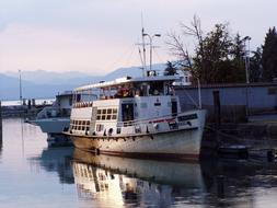 Boats in the lake port with plants, near the mountains, at colorful and beautiful sky on background