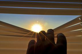 the view through the gap in the blinds into the bright sun