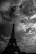 black and white photo of the eiffel tower under storm clouds