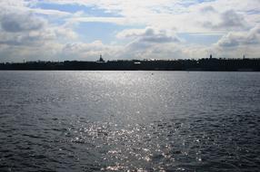 Beautiful River Neva in sunlight, with the coast with silhouettes, in Russia, under the blue sky with clouds