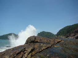 Beautiful rocky coast with waves, under the blue sky