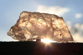 Close-up of the beautiful, shiny quartz stone, at background with landscape and sunlight