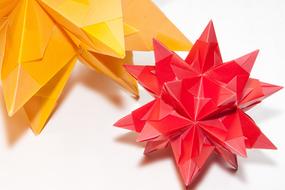 Close-up of the colorful and beautiful origami shapes, with shadows, on the white surface