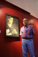 Man artist near the colorful painting on the red wall