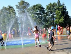 People with colorful toys, having fun with the water fountain in Canada