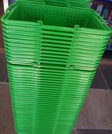 Stack of the shiny green shopping baskets in the building