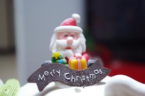 Beautiful and colorful cake figure of Santa Claus with gifts and "Merry Christmas" sign