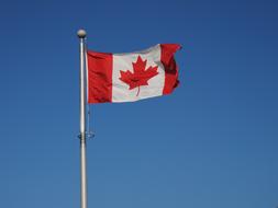 flag of canada on a flagpole against a blue sky
