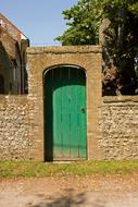 Stone building with the green, wooden door, near the plants