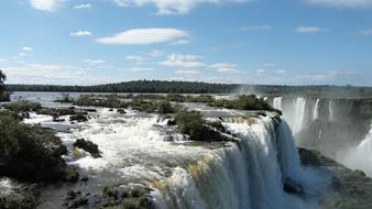 Beautiful landscape of the Foz Do IguaÃ§u waterfall with plants, in Brazil, under the blue sky with clouds