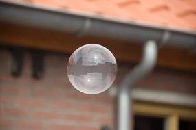 Close-up of the colorful, shiny, flying soap bubble near the building