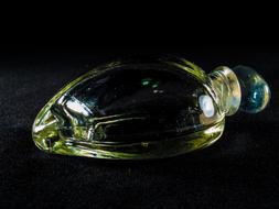 Close-up of the beautiful, shiny, green perfume glass bottle of different shades, at black background