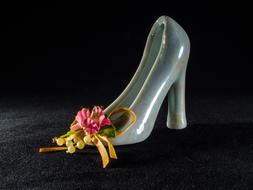 Close-up of the beautiful and colorful, shiny kid shoe figure with flower, at dark background