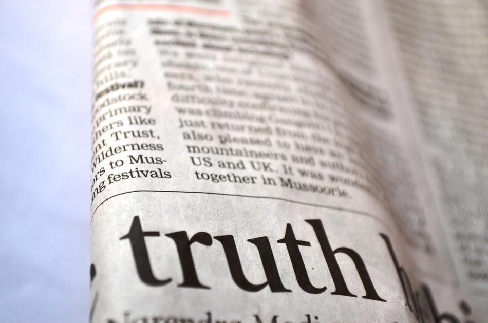 Close-up of the black 'truth' sign on the newspaper