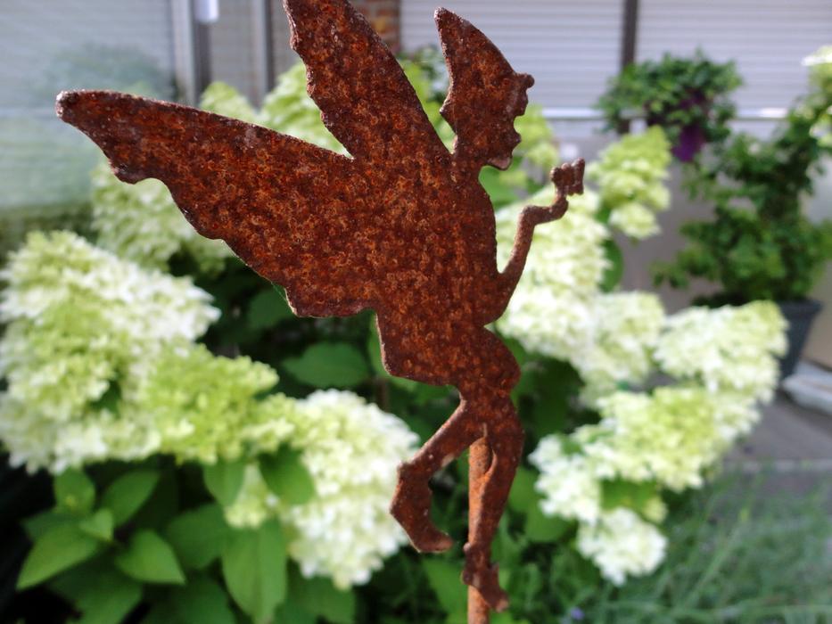 Close-up of the rusty 'fairy' flower plug near the beautiful and colorful flowers with green leaves