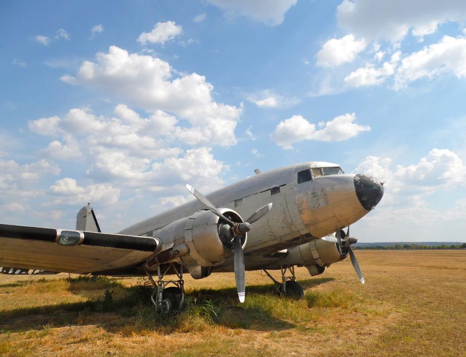 Dc-3 aircraft on the field, on landscape, under the blue sky with clouds