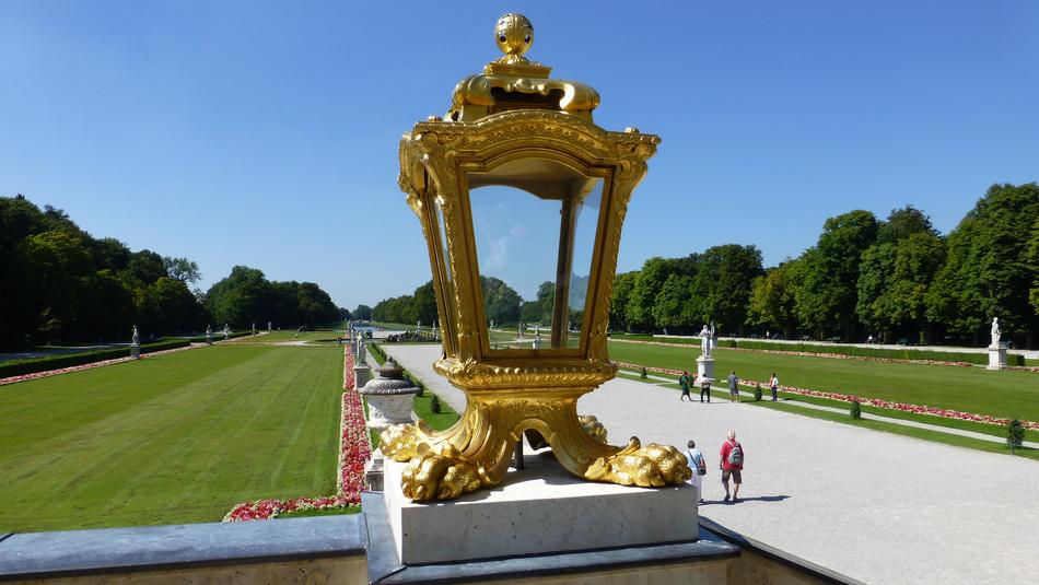 Beautiful, shiny, gold lantern among the colorful plants, near the people, in Castle Nymphenburg, Munich, Bavaria, Germany