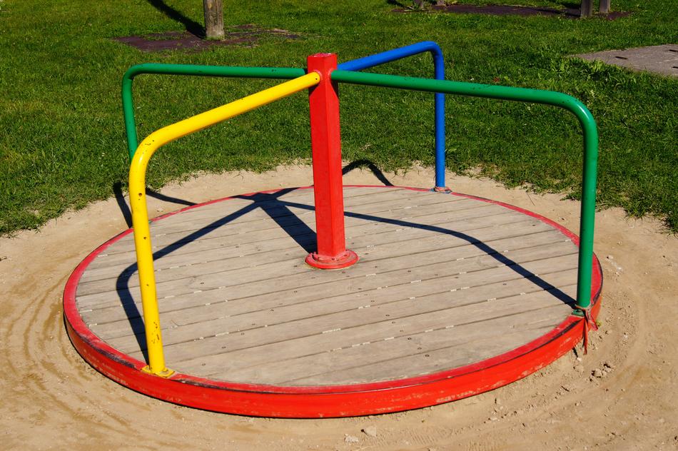 Colorful carousel among the sand and green grass, on the children's playground