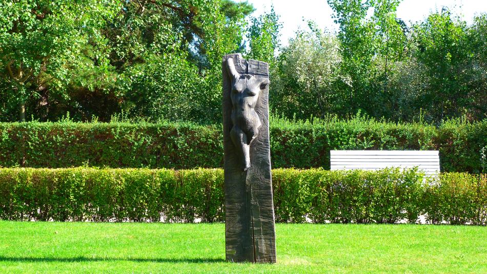 Statue with body, among the colorful and beautiful plants, in sunlight