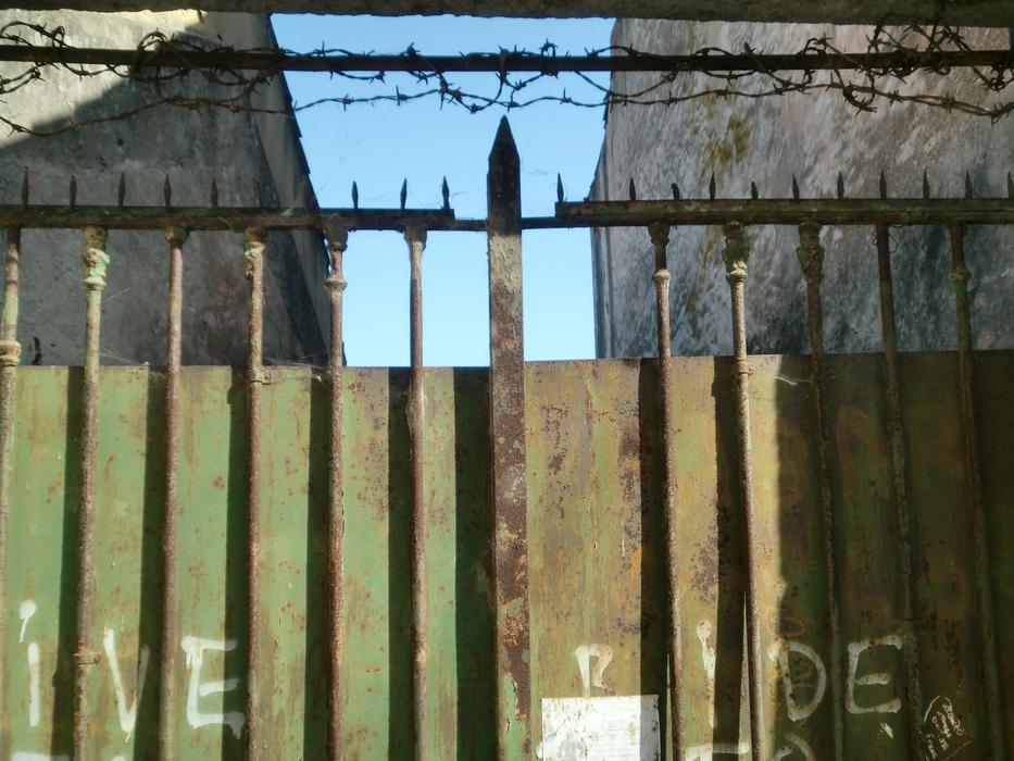 Fence with barbed wire, near the buildings, under the blue sky
