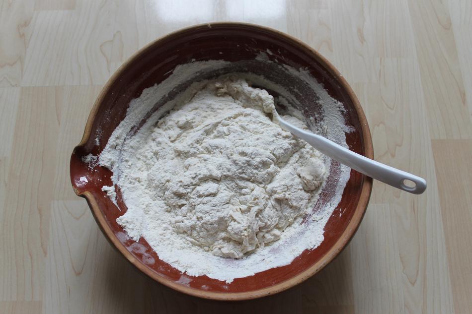 Mixing dough in bowl, with the spoon, on the wooden surface