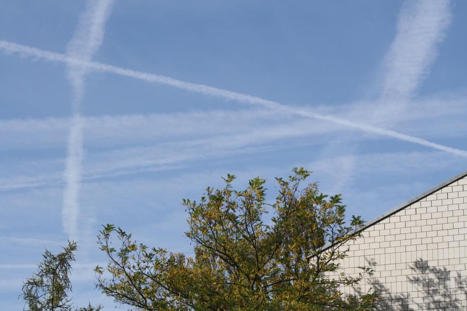 Building among the colorful trees, under the blue sky with white contrails