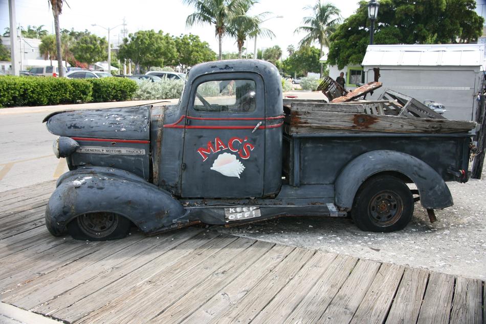 Side view of the old, rusty truck, near the trees, in Key West, Florida, USA