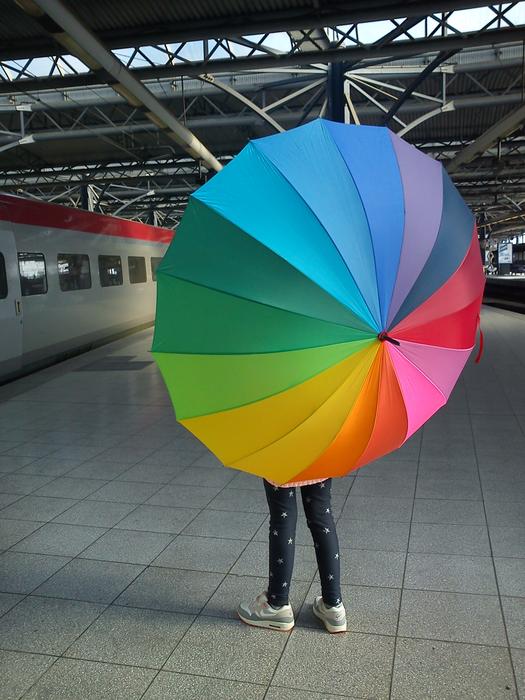 Person with the colorful umbrella, near the train, at the train station