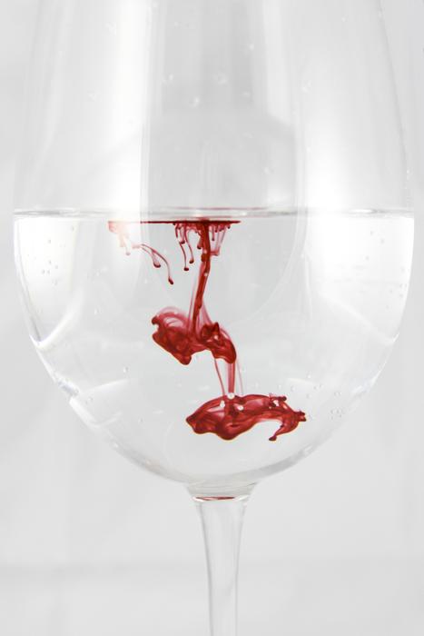 red paint dissolving in Glass Of Water