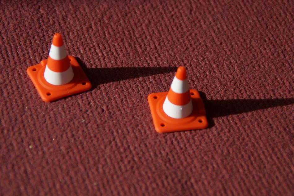 Orange and white hat pylons with shadows, in light