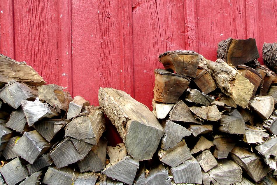 firewood near the red wall of the barn