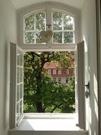 White window with the heart, and beautiful and colorful spring view with the plants and buildings