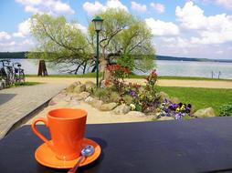 orange mug on table by shore
