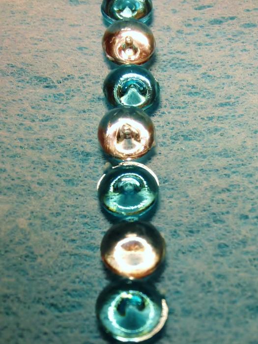 row of green and golden glass transparent beads on cloth