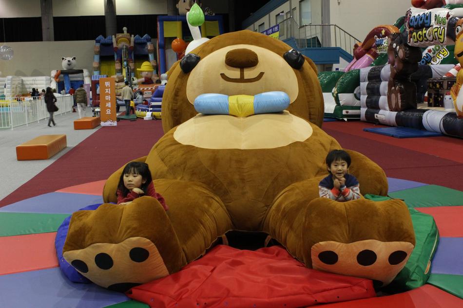 children and big teddy bear in the amusement park