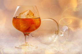 Brandy with ice cubes in glass, blur background