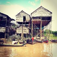 boats on Tonle Sap lake near traditional houses on pillars, Cambodia
