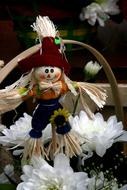 Colorful, cute and beautiful scarecrow figure, above the beautiful, white and green flowers