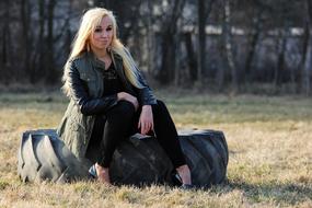 Blonde girl sitting on a car tire
