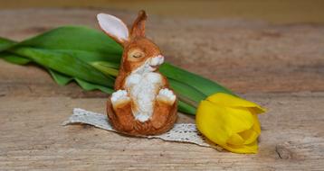 figurine of a brown hare near a yellow tulip