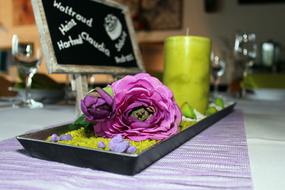 Close-up of the colorful and beautiful table decoration with the flower, candle and board