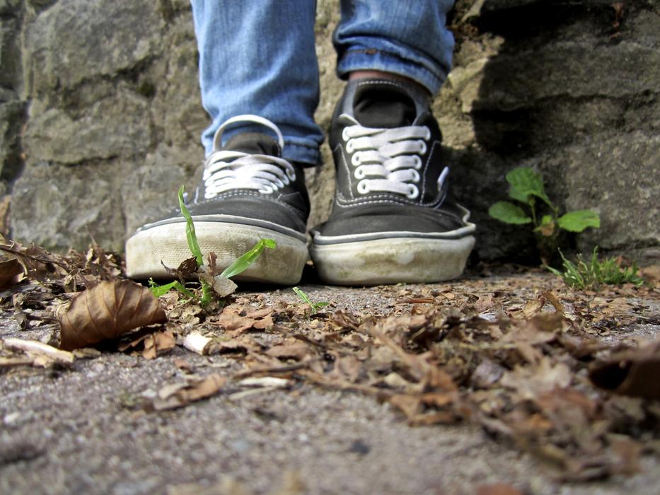 Feet of a man in sneakers near a wall