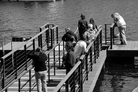 people resting on the bridge by the lake