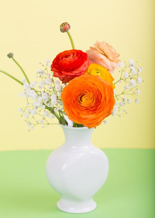 Shiny, white vase with the colorful and beautiful flowers, at colorful background