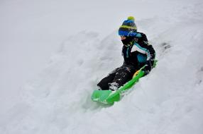 child rolling down a snow slide