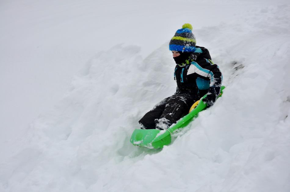 child rolling down a snow slide