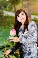 asian girl holding pink lotus in her hand